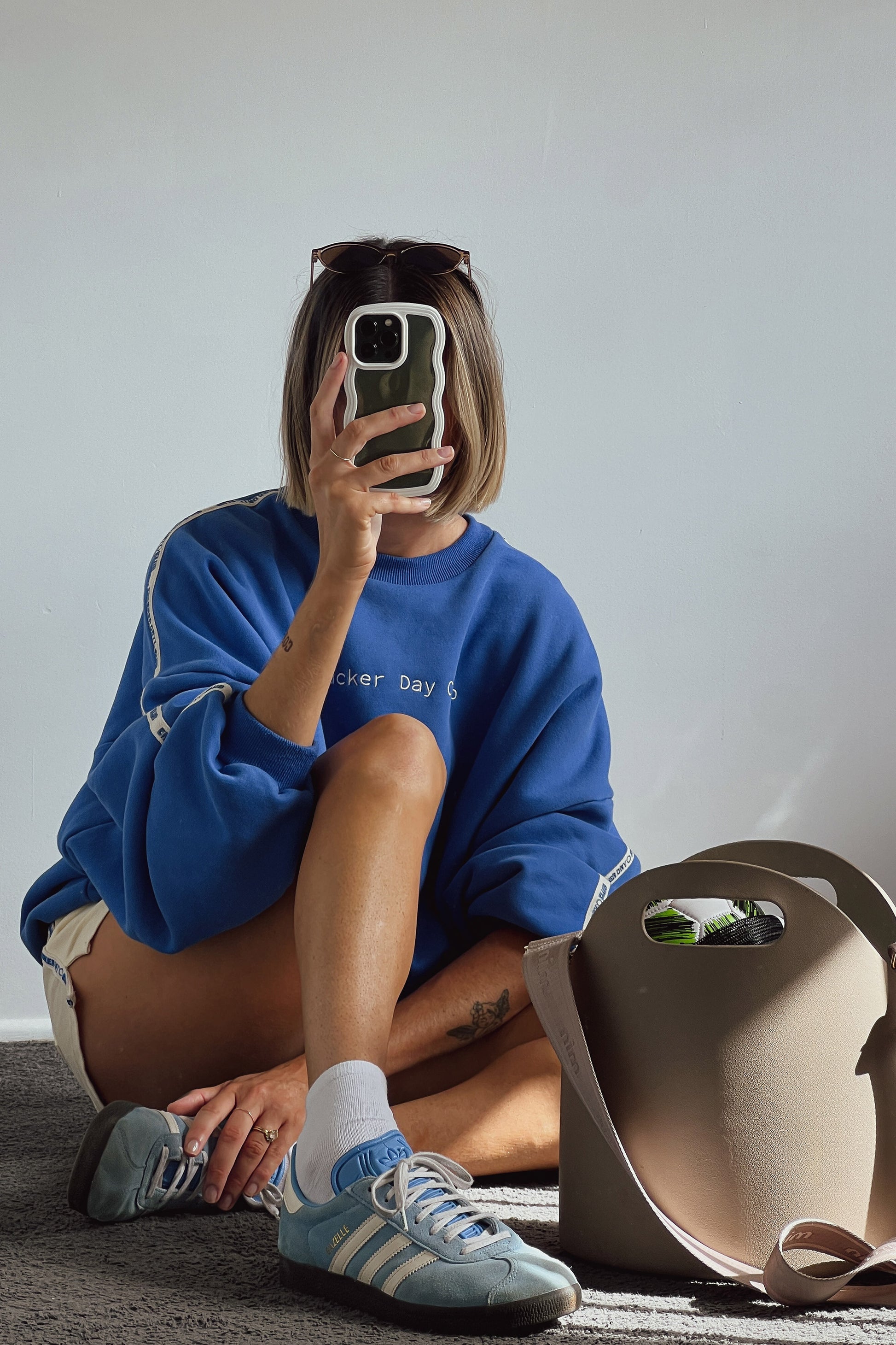 woman wearing cloud racer sweater in blue with cracker day club embroidery on the sleeve