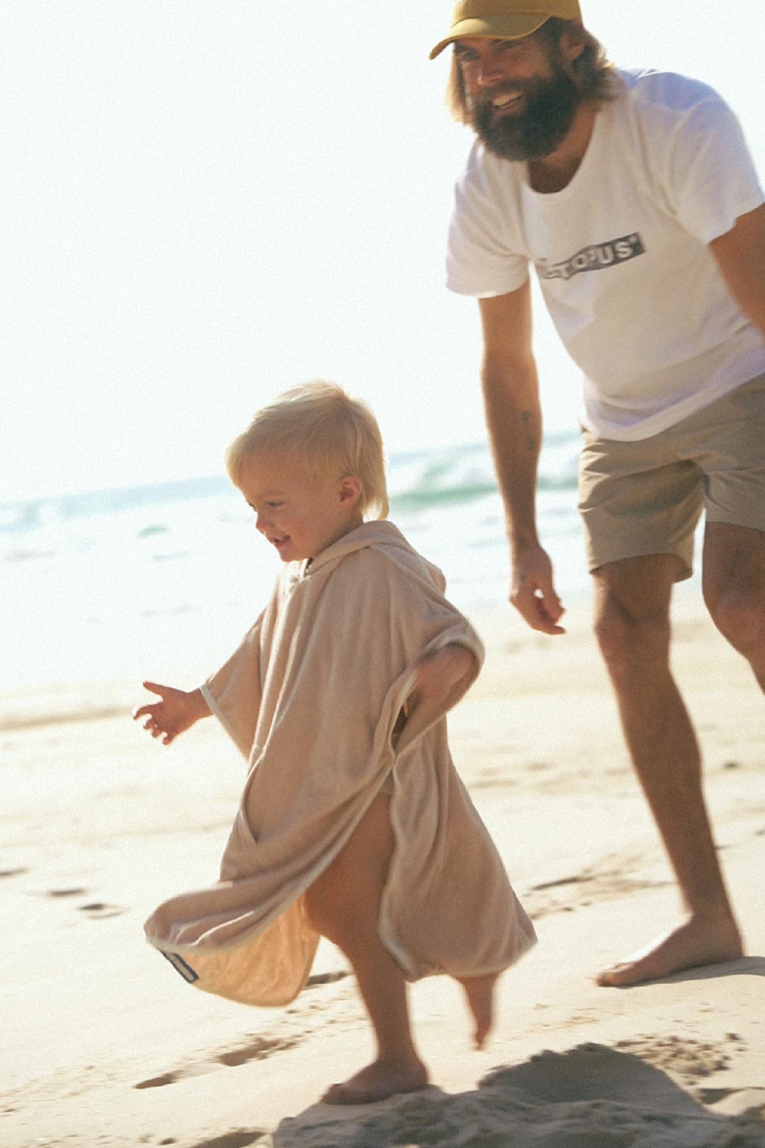 dad chasing toddler on the beach wearing a hoodie towel made for boy and girls