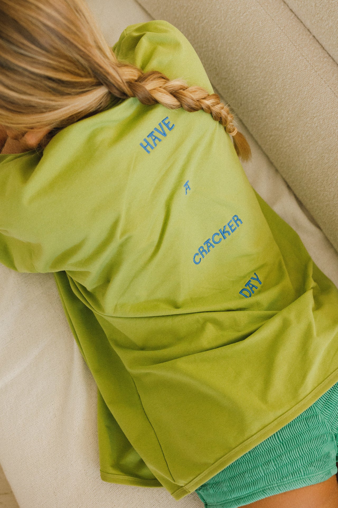 Woman wearing a green t-shirt with blue star designs against a stone wall.
