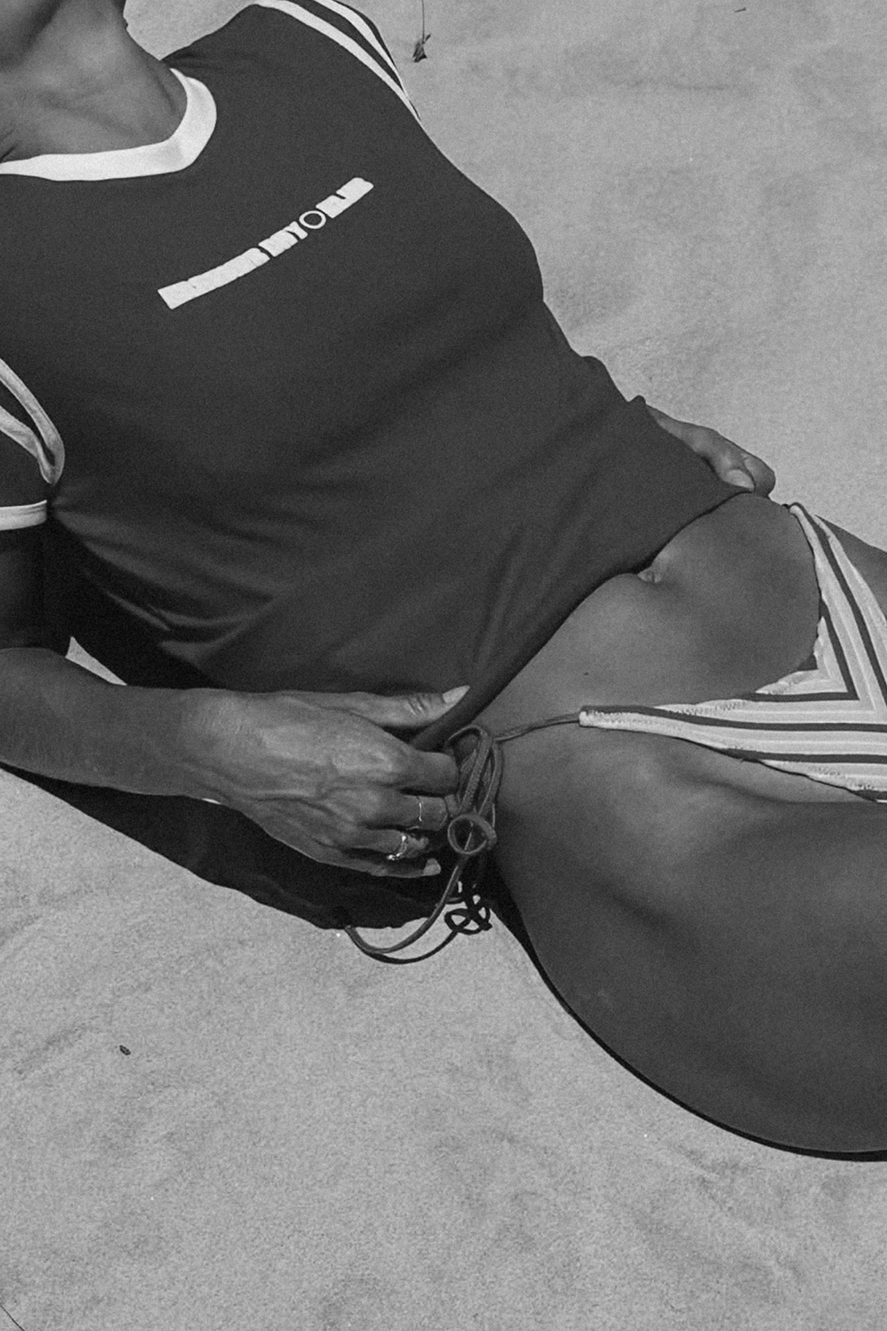 Person wearing a red cracker day club baby tee and bikini bottoms on a beach