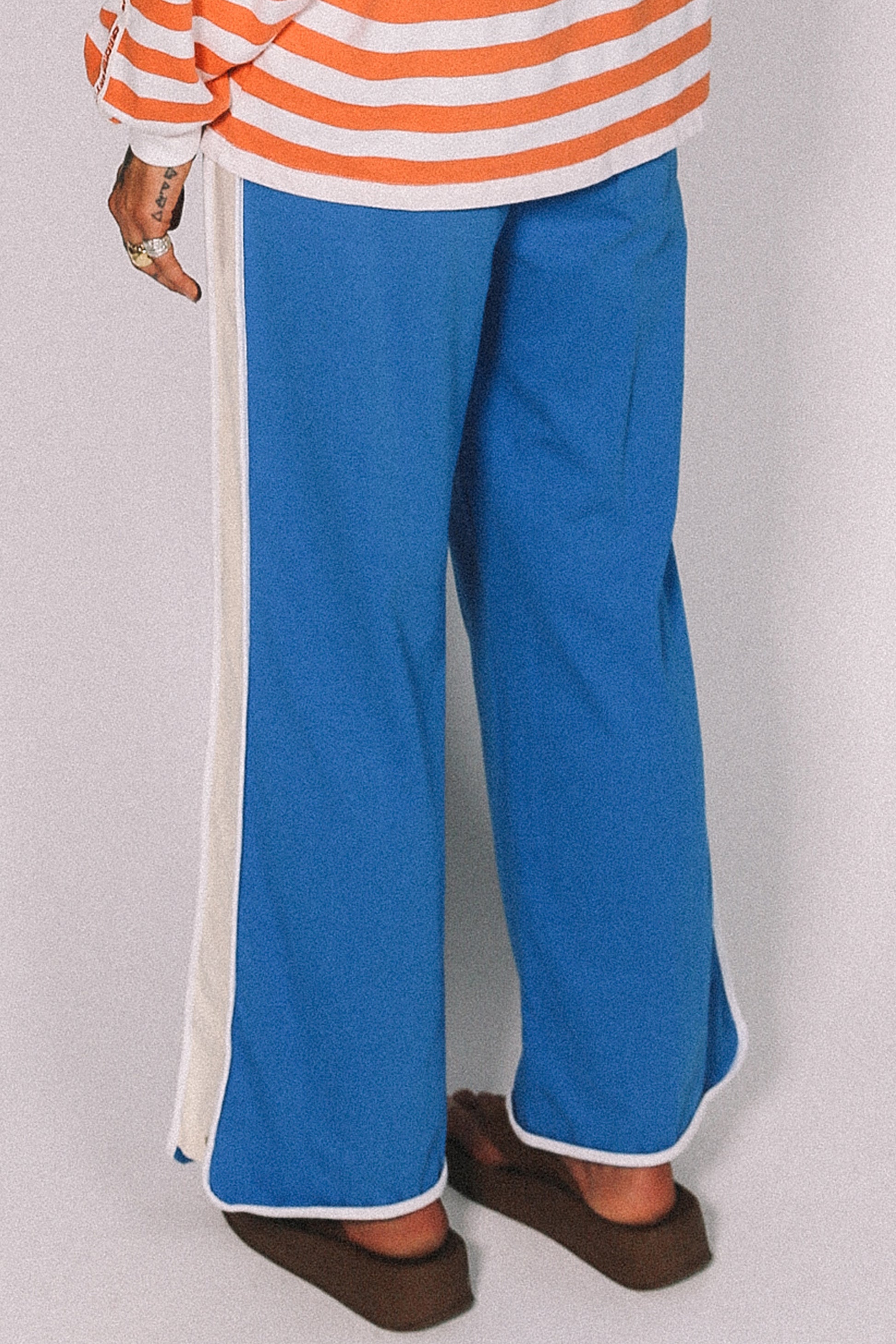 Person wearing blue pants with white stripes on a plain background