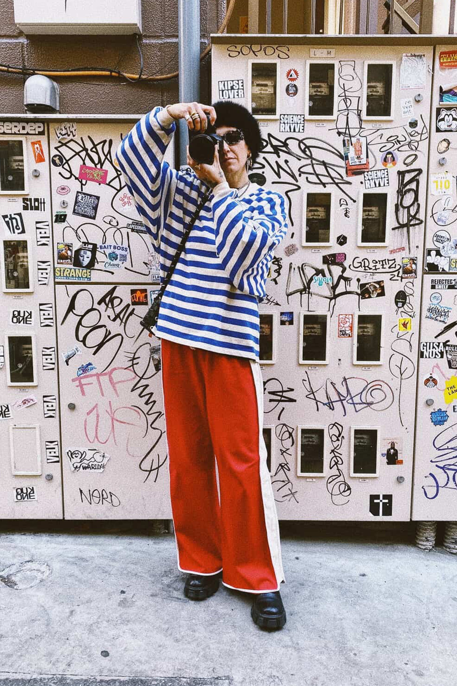 Person taking a selfie in front of a graffiti-covered wall