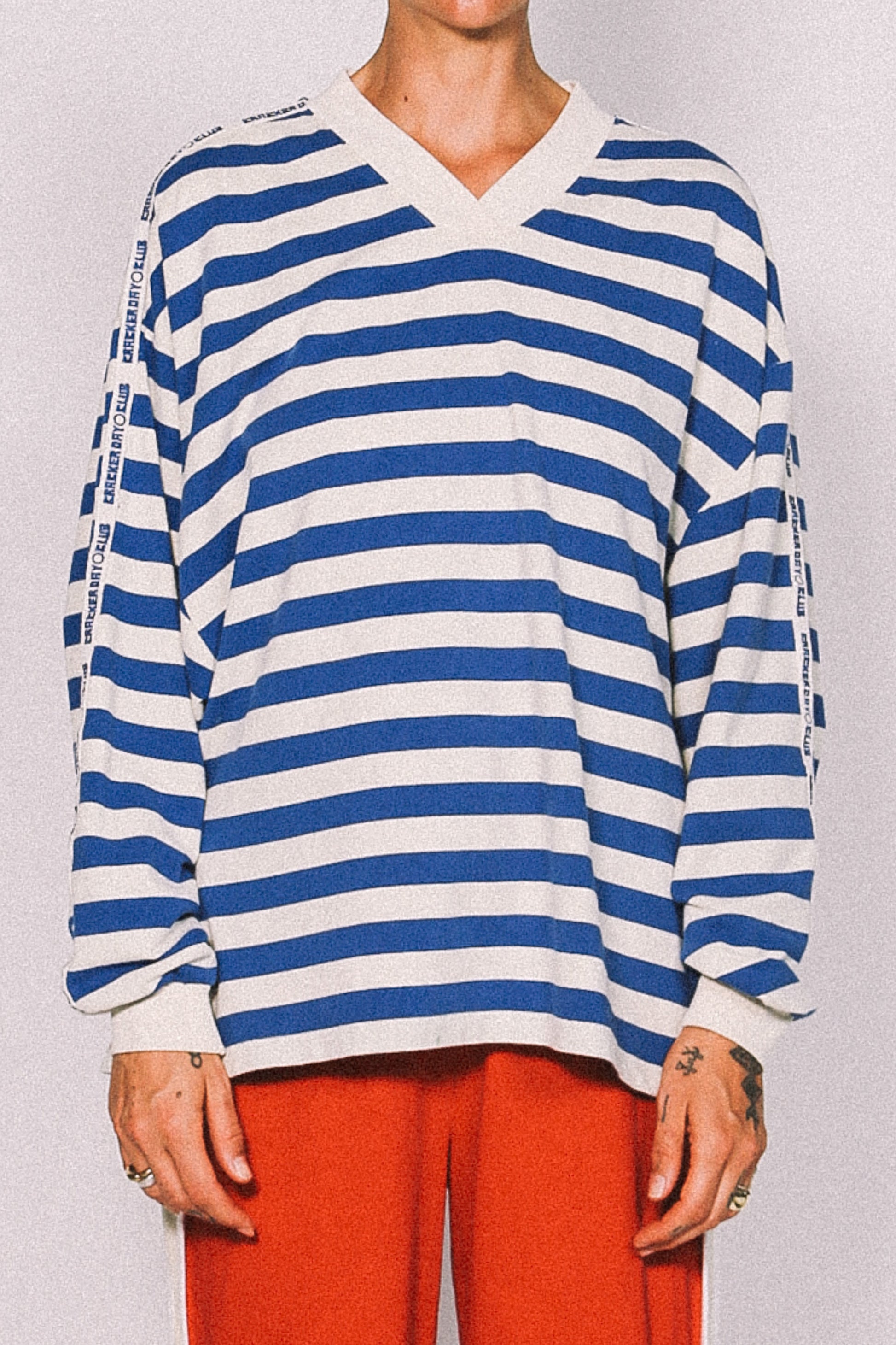Person wearing a blue and white striped shirt with red pants on a plain background