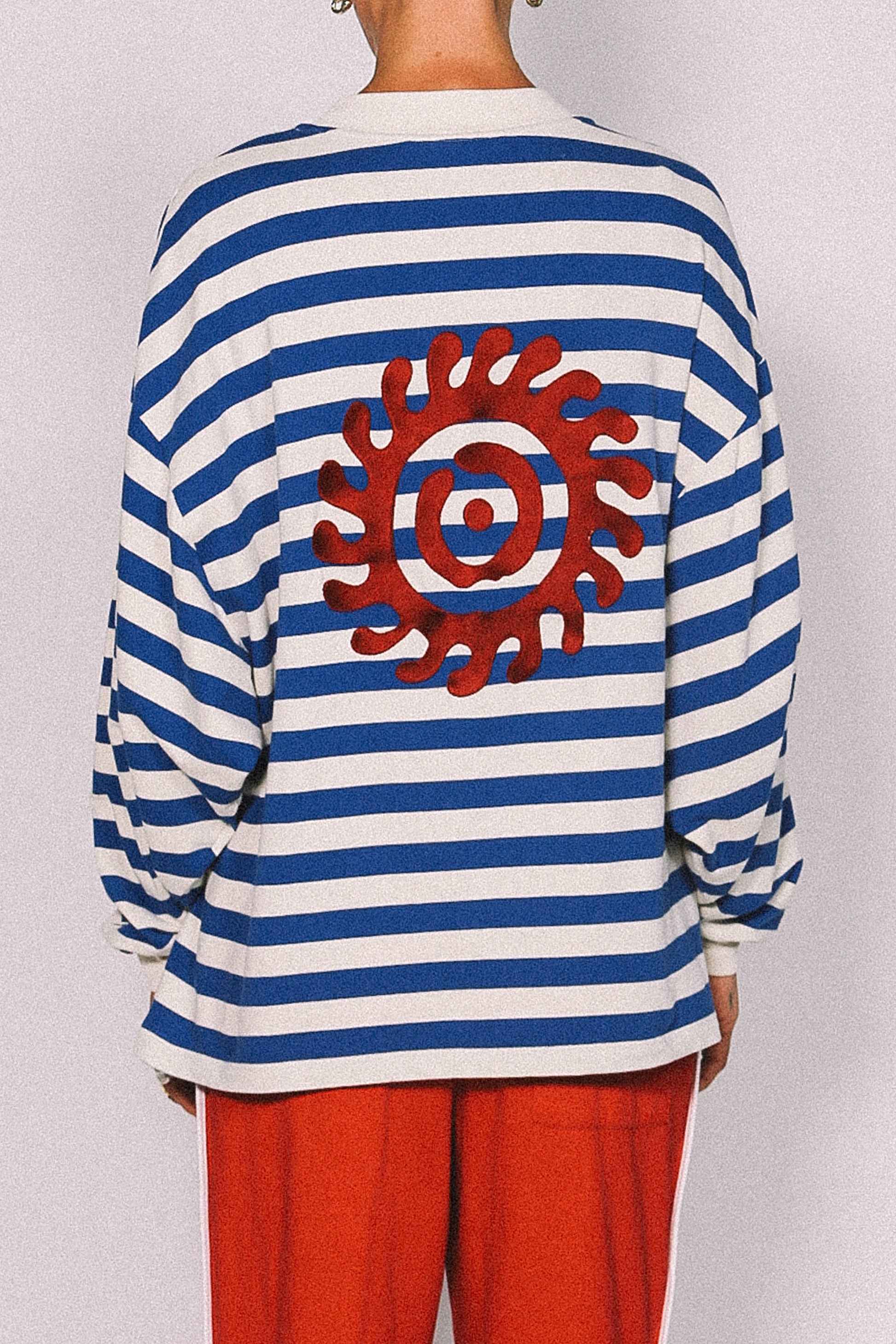 Blue and white striped shirt with a red sun design on a plain background