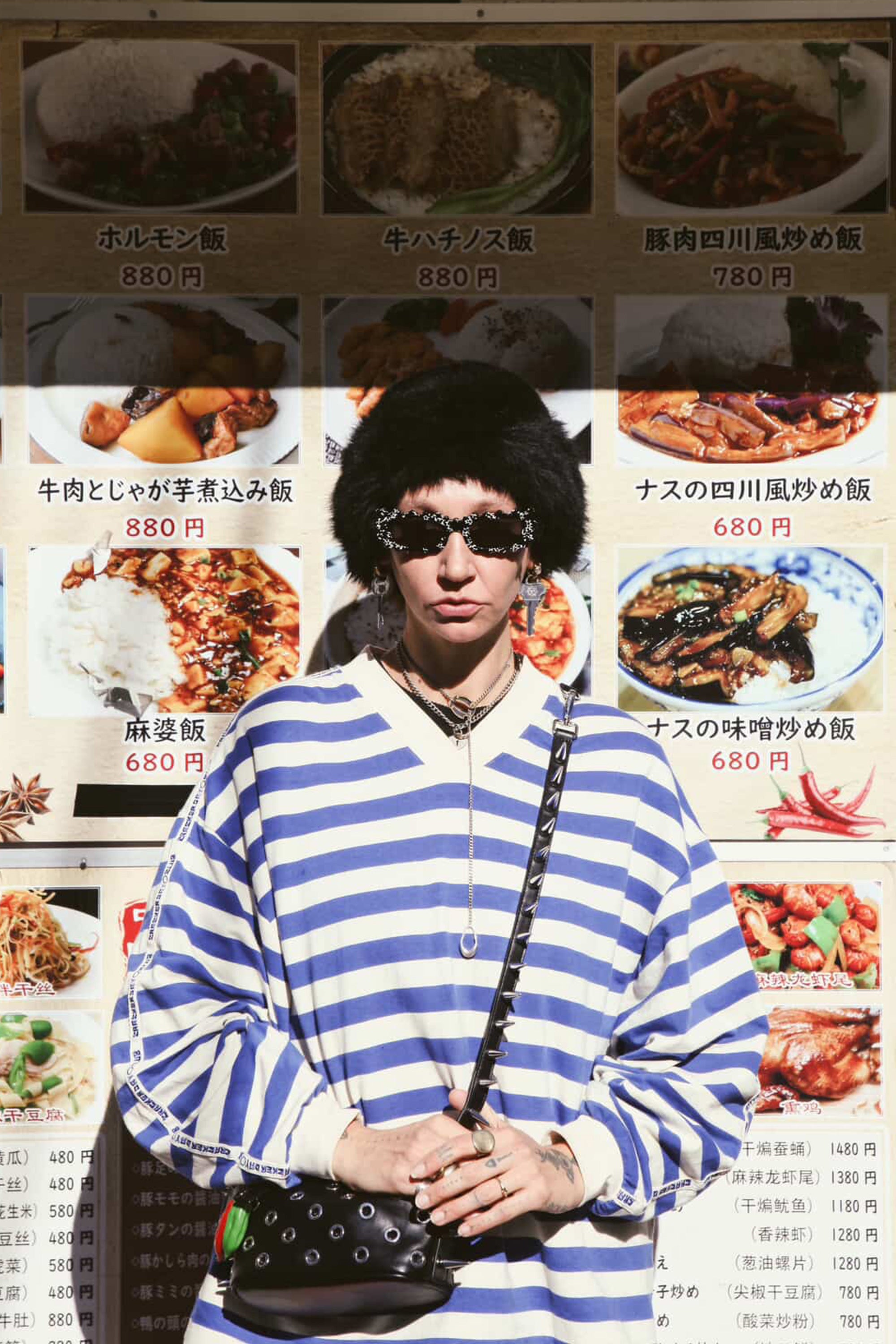 Person wearing a striped sweater with a menu of Japanese dishes in the background