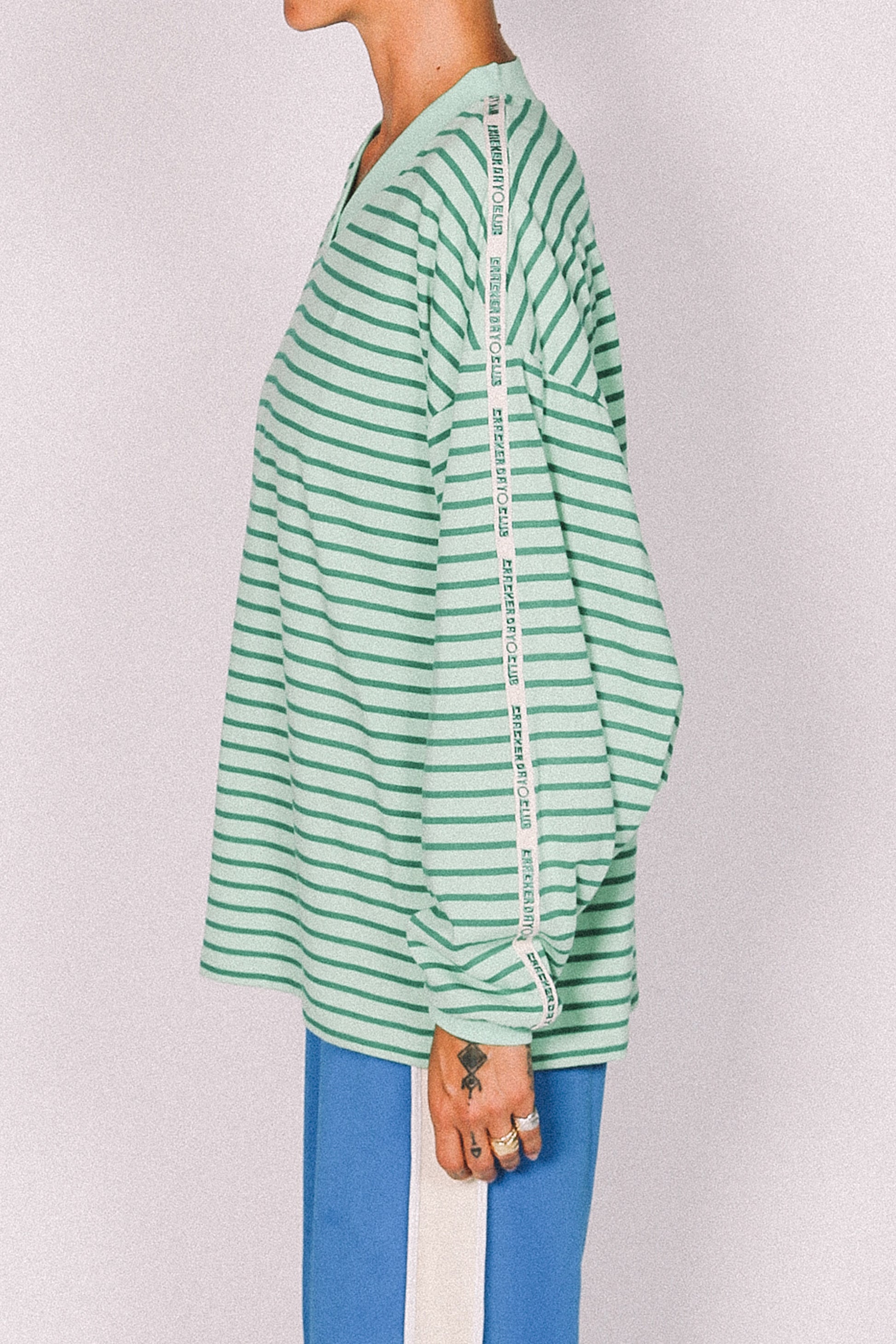 Green and white striped shirt worn by a person on a plain background