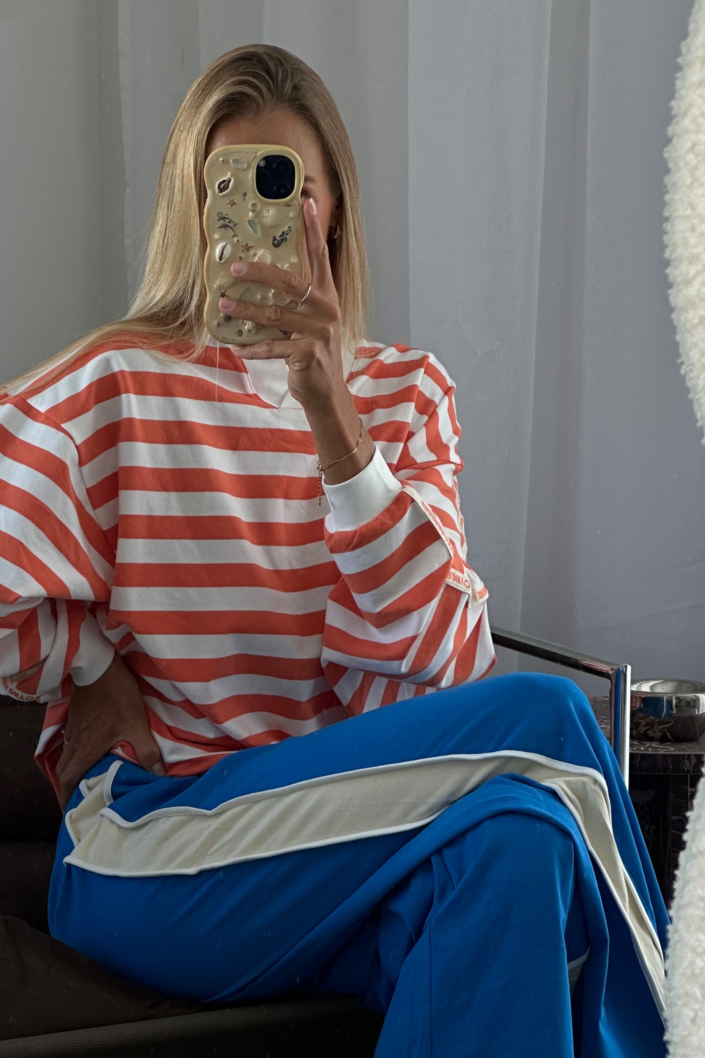 Person wearing a red and white striped shirt and blue pants sitting on a chair.