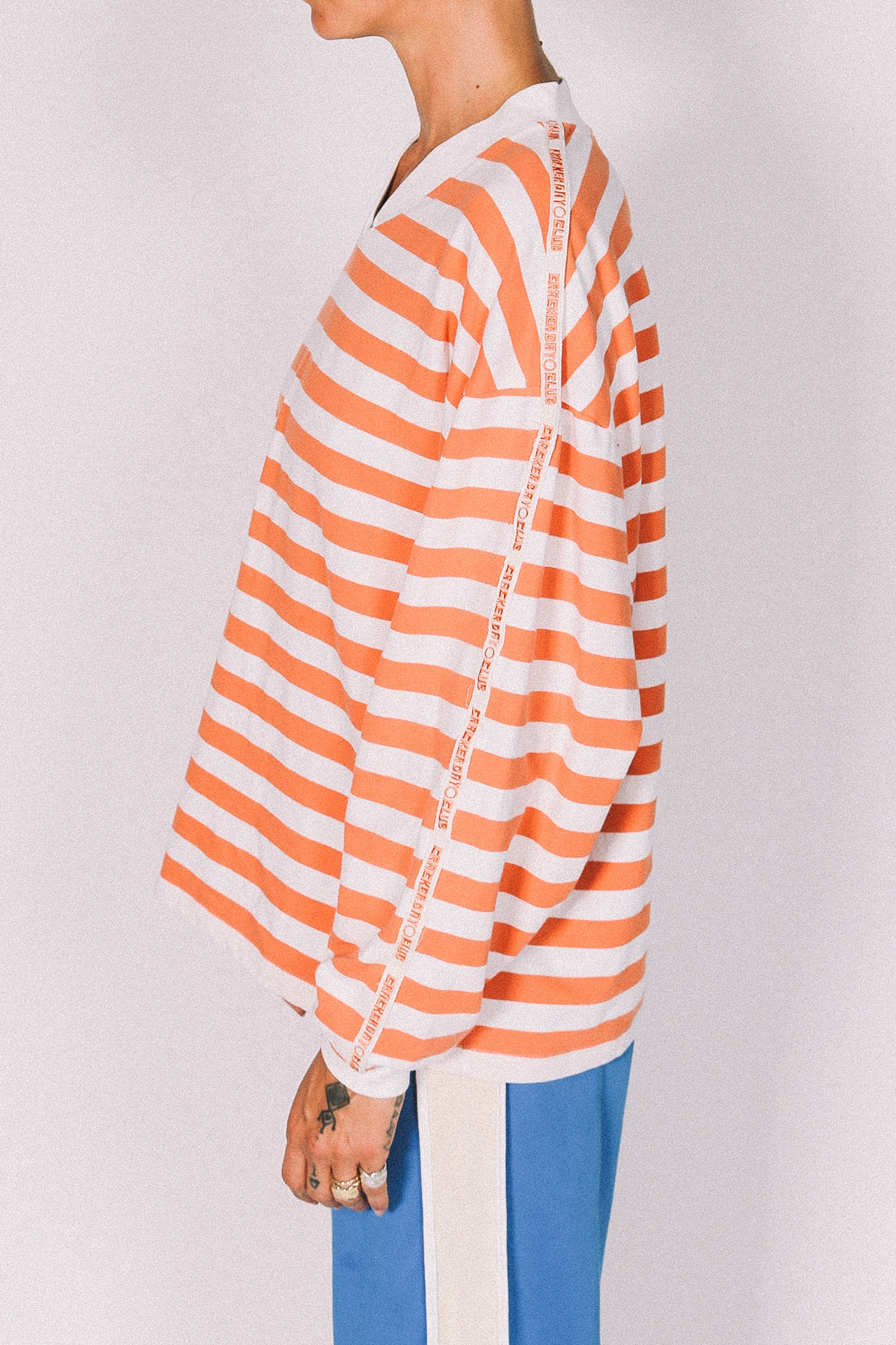 Person wearing an orange and white striped shirt with a plain background
