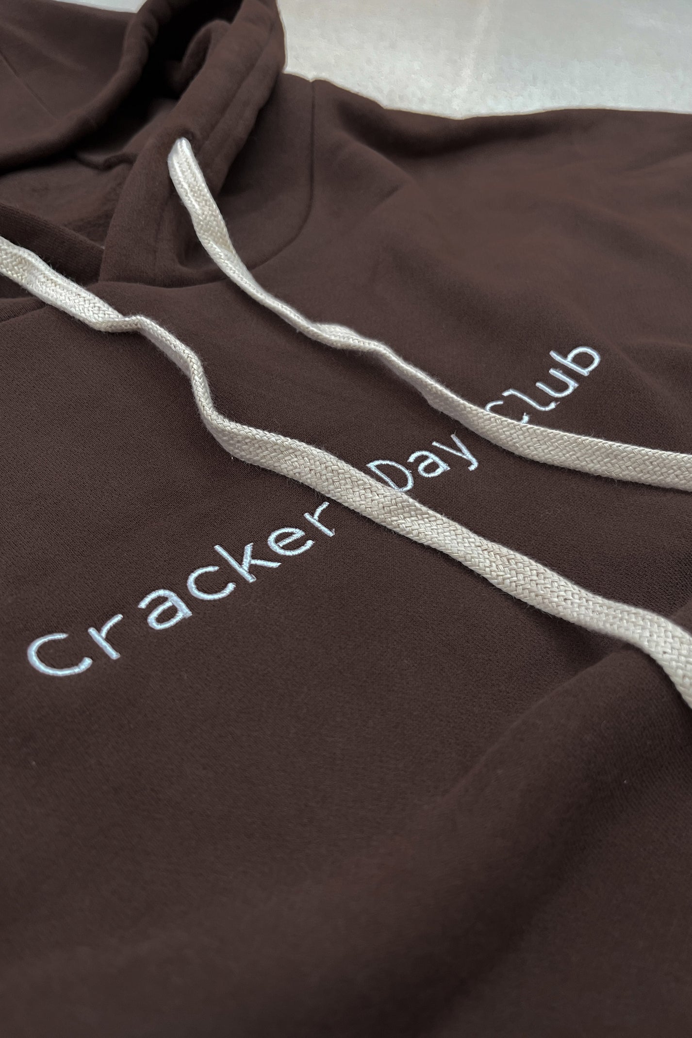 cloud racer hoodie in brown by cracker day club close up of embroidery and hood