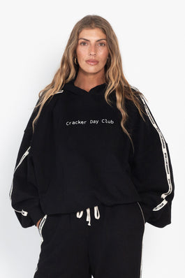 Person wearing a black hoodie with 'Cracker Day Club' text on a white background