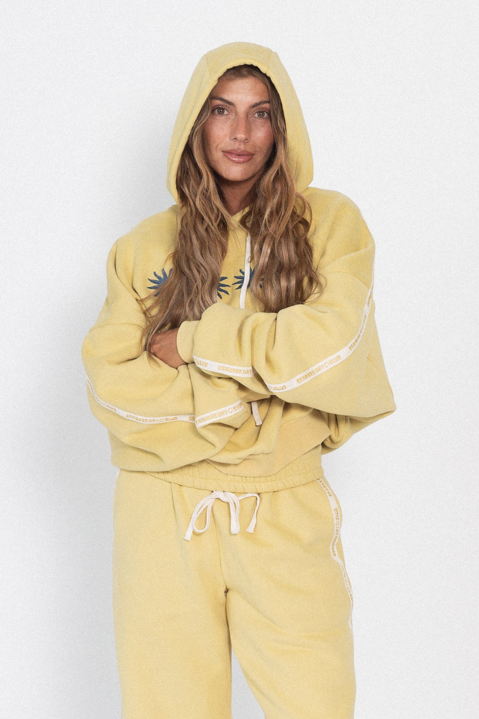Person wearing a yellow hoodie and pants set on a white background