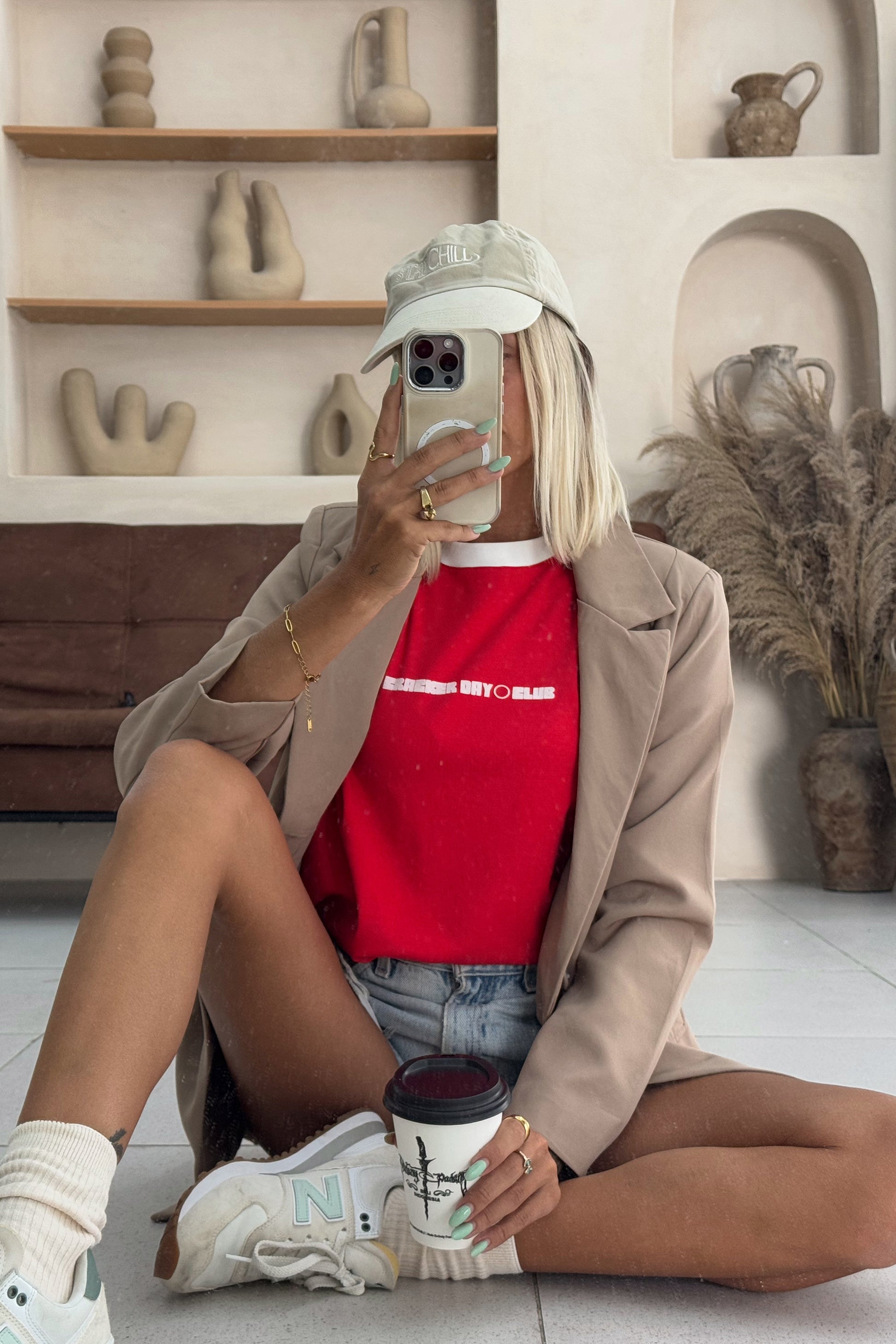 red womens tee styled with coat and denim shorts