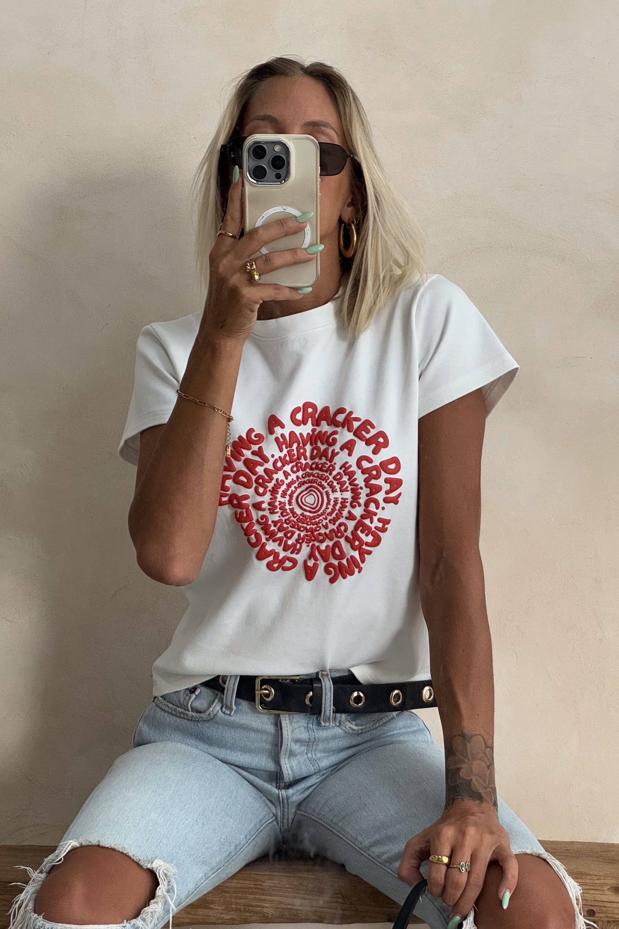 white baby tee styled with ripped denim jeans on a blonde woman